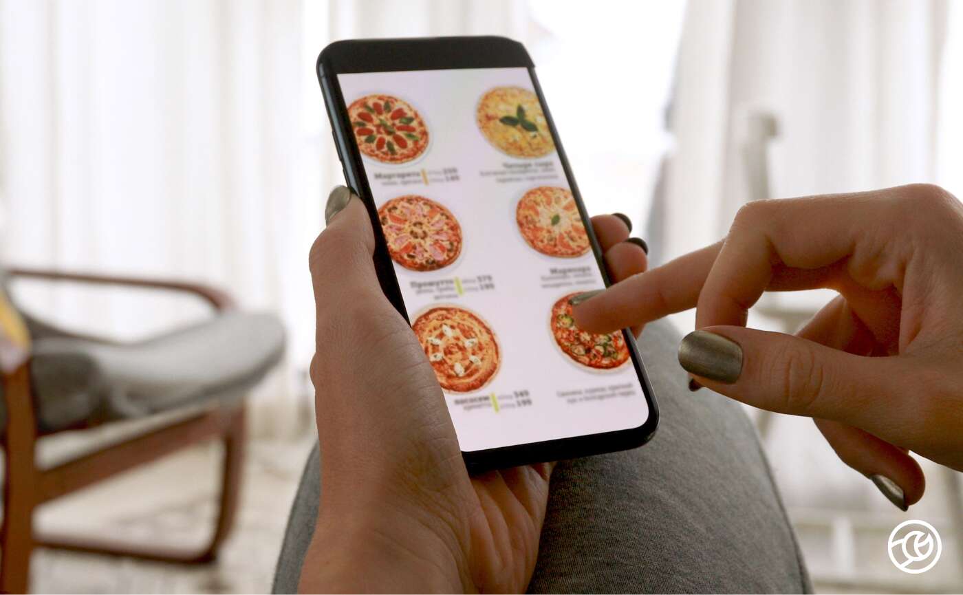 someone holding a phone with pizza on the screen